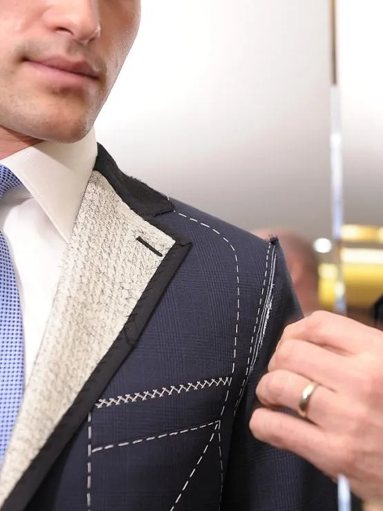 Master tailor adjusting a basted bespoke suit jacket fitting with floating canvas stitching at Arta Tailoring in St James's London
