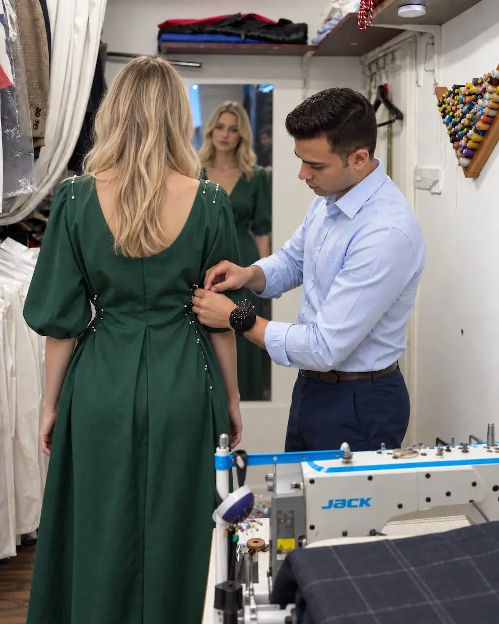 Master tailor fitting and pinning a green evening dress for a client at Arta Tailoring in St James's London